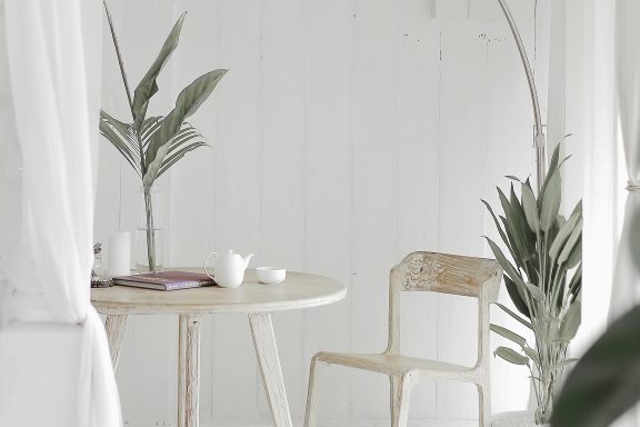 Intérieur minimaliste avec une table, une chaise en bois et des plantes vertes.